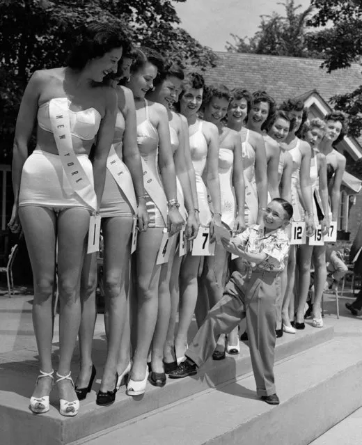 At a beauty contest to select the nation's Queen of Height during the first national convention of Tall People's Clubs in New York on July 29, 1949, little Charlie Young, only three feet, eleven inches tall, acting as judge, had a tough time making up his mind for the choice. The national minimum height requirement for women members is 5 feet 10 inches, and for men, 6 feet. (Photo by Robert Kradin/AP Photo)
