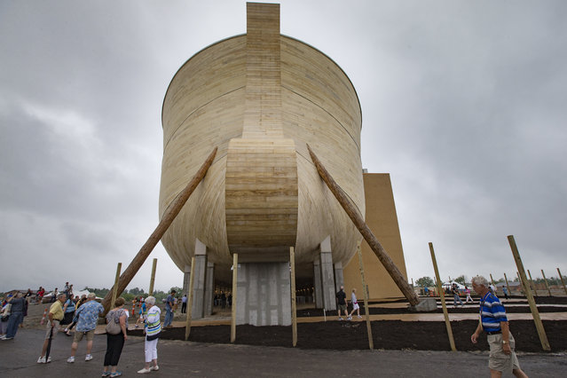 Visitors roam around a replica Noah's Ark as rain clouds pass overhead at the Ark Encounter theme park during a media preview day, Tuesday, July 5, 2016, in Williamstown, Ky. The long-awaited theme park based on the story of a man who got a warning from God about a worldwide flood will debut in central Kentucky this Thursday. The Christian group behind the 510 foot-long wooden ark says it will demonstrate that the stories of the Bible are true. Its construction has rankled opponents who say the attraction will be detrimental to science education. (Photo by John Minchillo/AP Photo)