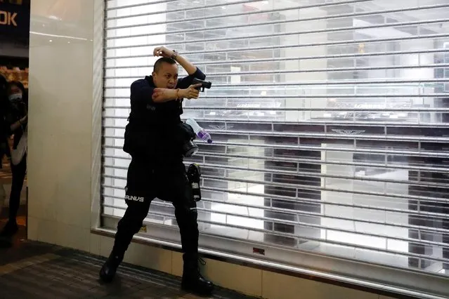 A police officer points his gun towards anti-extradition bill protesters after a clash, at Mong Kok, in Hong Kong, February 29, 2020. The officer drew his gun but did not fire as protesters hurled plastic water bottles and umbrellas at him, during a rally to mark six months since the authorities stormed a subway station and arrested demonstrators. (Photo by Tyrone Siu/Reuters)