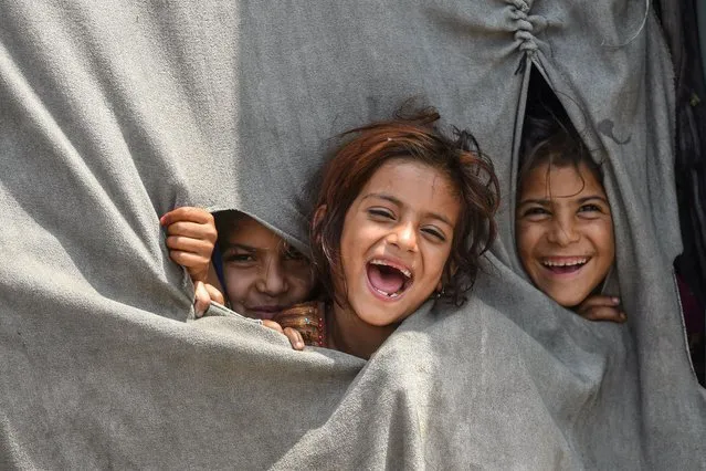 Children of Afghan refugees living in Pakistan react to the camera from inside their makeshift tent on the outskirts of Lahore on June 19, 2022, on the eve of “World Refugee Day”. (Photo by Arif Ali/AFP Photo)