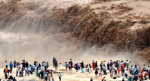 People visit the Hukou Waterfall on the Yellow River on the border area between Jixian County of north China's Shanxi and Yichuan County of northwest China's Shaanxi provinces, August 24, 2017. Due to heavy rainfall at the upper reaches, the water volume of Hukou Waterfall surged. (Photo by Lyu Guiming/Xinhua/Barcroft Images)