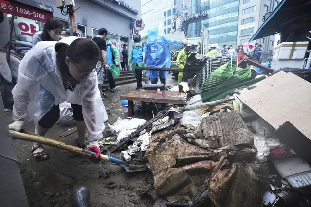 A woman cleans up debris after the water drained from a submerged traditional market following heavy rainfall in Seoul, South Korea, Tuesday, August 9, 2022. Heavy rains drenched South Korea's capital region, turning the streets of Seoul's affluent Gangnam district into a river, leaving submerged vehicles and overwhelming public transport systems. (Photo by Ahn Young-joon/AP Photo)