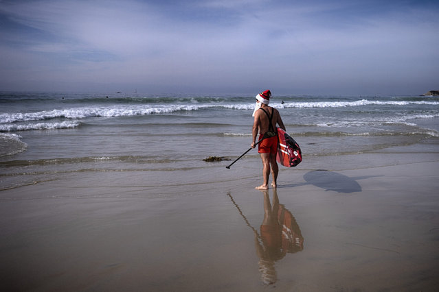 Andre Ausseresses takes to the waves with his paddle board during the Surfing Santa event in Dana Point, Calif. on Sunday, December 8, 2024. (Photo by Richard Vogel/AP Photo)