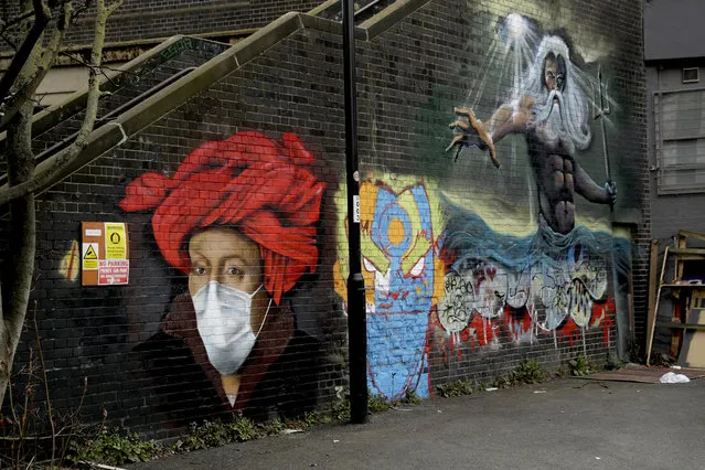 A mural by street artist Lionel Stanhope with a face mask reference to coronavirus next to one of his other works, at right, painted on a bridge wall in Ladywell, south east London, Thursday, April 2, 2020. (Photo by Matt Dunham/AP Photo)