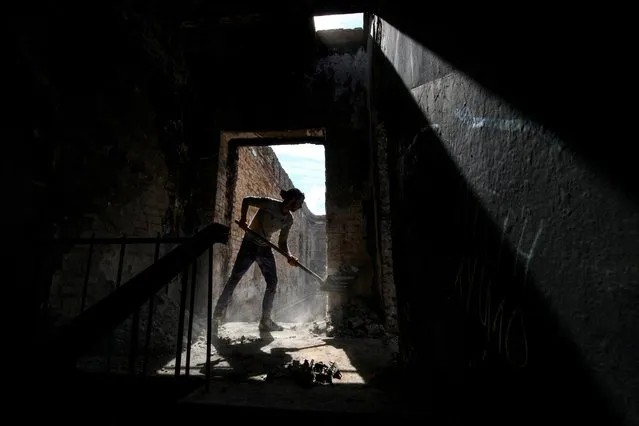 A volunteer removes debris from the House of a Culture in the village of Ivanivka, which was heavily damaged during Russia's attack on Ukraine, in Chernihiv region, Ukraine September 3, 2022. Members of the volunteers' movement Repair Together travel over regions, which were under Russian occupation, and help local residents to clean up damaged buildings under accompaniment of electronic music. (Photo by Vladislav Musienko/Reuters)