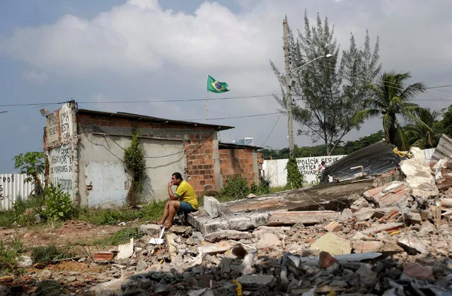 Marcio Moza sits in the debris of his just-demolished house in the Vila Autodromo community surrounded by construction work for the Rio 2016 Olympic Park, in Rio de Janeiro, Brazil, March 8, 2016. (Photo by Ricardo Moraes/Reuters)