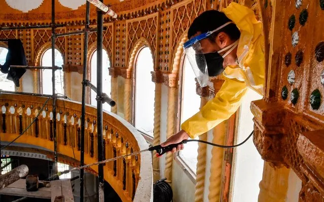 A civil association volunteer from the Hocine Dey commune sprays disinfectant as part of sterilisation efforts as part of a national campaign by Algeria's Ministry of Religious Affairs and the Wakf for COVID-19 coronavirus disease prevention, from outside the dome of the Abou Hanifa Enouemane mosque in the capital Algiers on May 19, 2020. (Photo by Ryad Kramdi/AFP Photo)