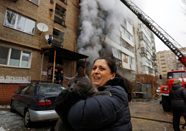 A woman holds her cat, which was carried by a firefighter out of an apartment building damaged by recent shelling in the course of Russia-Ukraine conflict in Donetsk, Russian-controlled Ukraine on December 19, 2023. (Photo by Alexander Ermochenko/Reuters)
