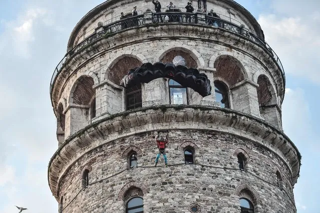 Turkish extreme sports athlete Cengiz Kocak performs a base jump off Galata Tower in Istanbul on November 9, 2017, as part of the events organised by European Outdoor Film Tour (EOFT) in Istanbul. Cengiz Kocak on November 9 base jumped from Istanbul's historical Galata Tower – the first of its kind in 385 years. Kocak made a safe parachute landing fall from a 36-metre height, becoming the second man after Hezarfen Ahmet Celebi, a legendary Ottoman aviator who jumped down from Galata Tower for his first flight over Istanbul. (Photo by Ozan Kose/AFP Photo)