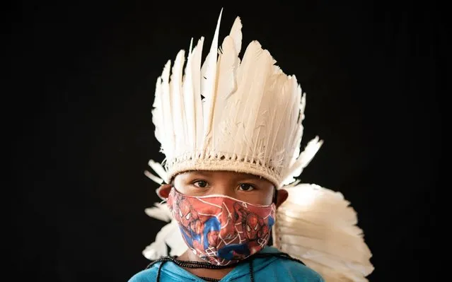 Six-year-old Ezinaldo dos Santos, of the Sater Maw indigenous ethnic group, poses for a portrait wearing the traditional dress of his tribe and a face mask amid the spread of the new coronavirus in the Gaviao community near Manaus, Brazil, Friday, May 29, 2020. (Photo by Felipe Dana/AP Photo)