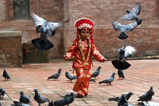 A girl dressed as a Kumari, a living goddess, runs after pigeons before taking part in “Kumari Puja” rituals at the Hanuman Dhoka in Durbar Square in Kathmandu on September 8, 2022. (Photo by Prakash Mathema/AFP Photo)