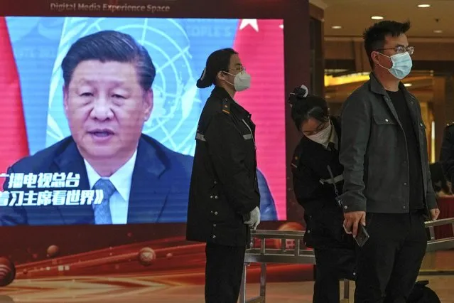 A security personnel checks on a journalist near a TV screen showing image of President Xi Jinping at a media hotel in Beijing, Friday, October 21, 2022. The Chinese Communist Party is holding its every-five-year national congress which will unveil new leadership for the coming five years. (Photo by Andy Wong/AP Photo)