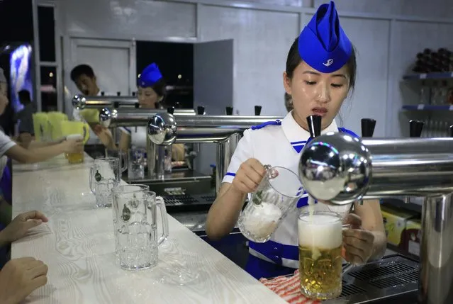 A beer server fills up glasses of draft beer at a beer festival held along the Taedong River on Friday, August 12, 2016 in Pyongyang, North Korea. (Photo by Kim Kwang Hyon/AP Photo)