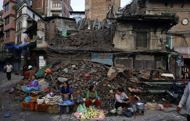 Nepalese vendors wait for customers in front of a collapsed house, a remnant of the April earthquake, in Kathmandu, Nepal, 20 September 2015. Nepal's President Ram Baran Yadav is  enacting the new constitution during aspecial function at the Constitution Assembly hall in Kathmandu on 20 September 2015. (Photo by Narendra Shrestha/EPA)