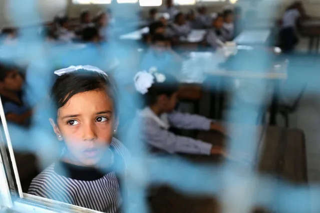 A Palestinian girl looks out of a classroom window as she attends a lesson on the first day of a new school year, at a United Nations-run school in Khan Young in the southern Gaza Strip August 28, 2016. (Photo by Ibraheem Abu Mustafa/Reuters)