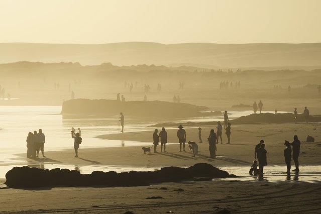 People walk along the beach at Birubi Point at sunset at Port Stephens north of Sydney, Australia, Friday, April 18, 2025. (Photo by Mark Baker/AP Photo)