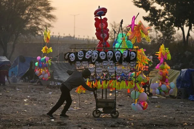 A migrant street vendor pushes his cart to work as he starts his day from his temporary shelter on a cold morning in Jammu, India, Wednesday, December 21, 2022. (Photo by Channi Anand/AP Photo)