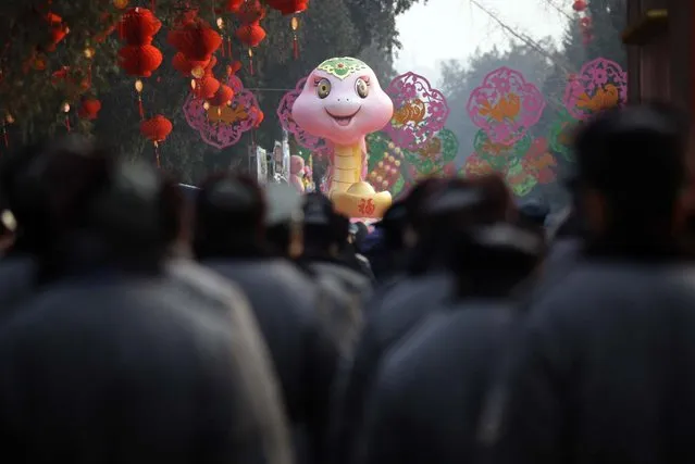 Security guards walk towards a snake sculpture as they gather for a security task of the Chinese Lunar New Year celebrations at Ditan Park (the Temple of Earth), in Beijing, February 9, 2013. The Lunar New Year, or Spring Festival, begins on February 10 and marks the start of the Year of the Snake, according to the Chinese zodiac. (Photo by Jason Lee/Reuters)
