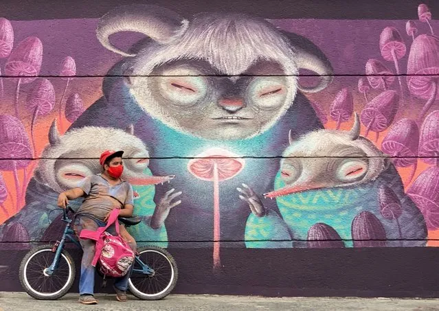 A man wears a face mask as a preventive measure against the spread of the novel coronavirus, COVID-19, as he stands next to a mural in Cali, Colombia, on July 21, 2020. (Photo by Luis Robayo/AFP Photo)