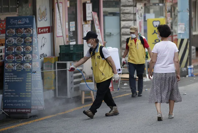 People disinfect as a precaution against the coronavirus in Seoul, South Korea, Saturday, August 29, 2020. Health officials prepare to tighten distancing restrictions in the greater capital area. (Photo by Lee Jin-man/AP Photo)