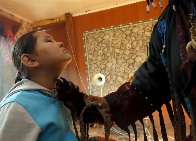 A female shaman Saida Mongush uses a paw of a bear as she conducts a medical session to cure a 9-year-old girl Norzhunmaa, who suffers from spinal curvature as a result of a patrimonial trauma, at her house in the town of Kyzyl, the administrative centre of Tuva region, Southern Siberia, Russia, October 7, 2015. The region is inhabited by Tuvans, historically cattle-herding nomads, who nowadays practise two main confessions – Buddhism and Shamanism. (Photo by Ilya Naymushin/Reuters)