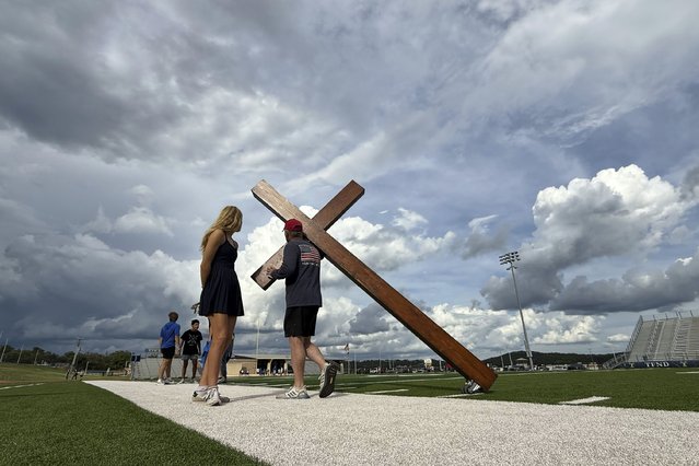 Dan Beazley, of Mich., center right, carries a large cross before a vigil for flooding victims at Tivy Antler Stadium on Wednesday, July 9, 2025, in Kerrville, Texas. (Photo by Gerald Herbert/AP Photo)