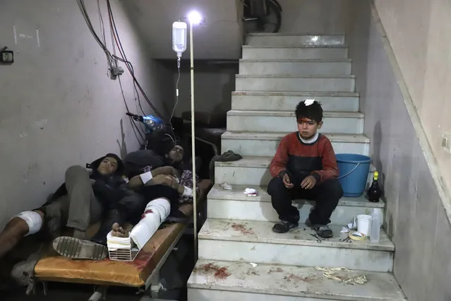 Wounded Syrians wait to receive treatment at a make-shift hospital in Kafr Batna in the besieged Eastern Ghouta region on the outskirts of the capital Damascus following Syrian government bombardments on February 21, 2018. Syrian jets carried out more deadly raids on Eastern Ghouta as Western powers and aid agencies voiced alarm over the mounting death toll and spiralling humanitarian catastrophe. (Photo by Amer Almohibany/AFP Photo)