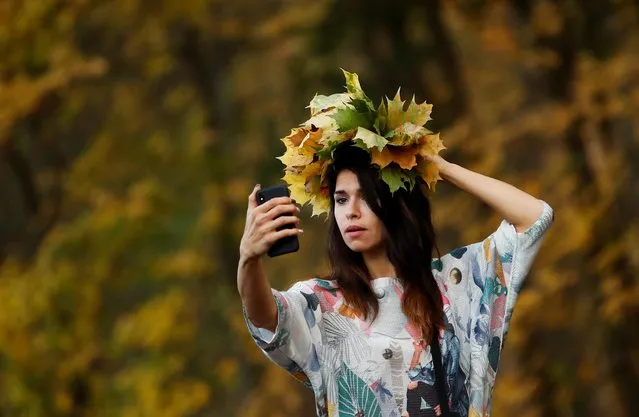A woman takes a selfie with yellow leaves in a park in Moscow, Russia on October 14, 2020. (Photo by Maxim Shemetov/Reuters)