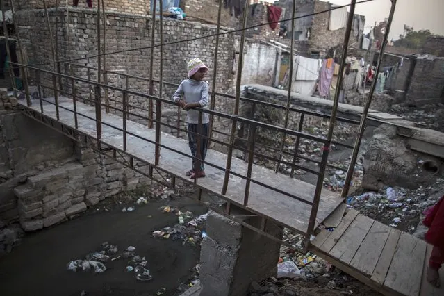 A girl looks back as she stands above an open sewer outside her house at a slum in Islamabad December 4, 2014. (Photo by Zohra Bensemra/Reuters)