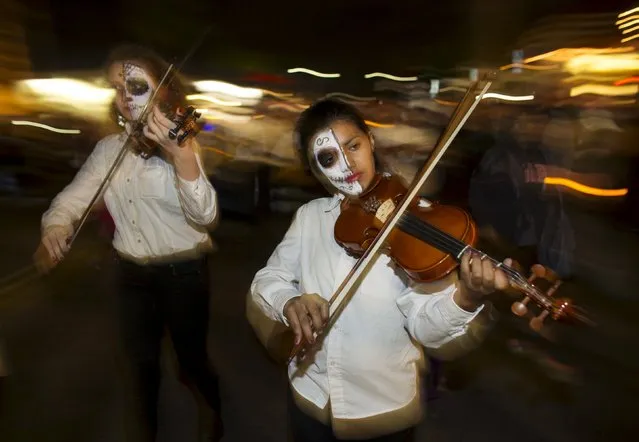 Participants play violins as they march during a candlelight procession at the end of a three-day "Day of The Dead" (Dia de los Muertos) celebration, which saw hundreds walk to El Campo Santo cemetery, in Old Town San Diego, California, November 2, 2015. (Photo by Mike Blake/Reuters)