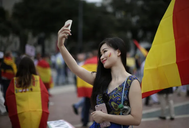 A woman takes a selfie surrounded by Spanish flags during the celebration for Spain's National Day in Barcelona, Spain, Wednesday, October 12, 2016. (Photo by Manu Fernandez/AP Photo)