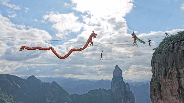 A slackline walker performs dragon dance at Shenxianju scenic area on September 22, 2025 in Taizhou, Zhejiang Province of China. The 2025 Shenxianju Cup China International Slackline Open is being held from Saturday to Tuesday at the scenic area. (Photo by Wang Huabin/VCG via Getty Images)