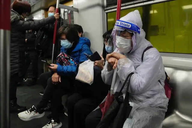 A woman wearing a face mask and face shield, sits in a train in Hong Kong, Wednesday, February 23, 2022. Hong Kong residents are becoming increasingly annoyed with the administration’s insistence on sticking to China's “zero-COVID” strategy as the city posted another record number of new cases Wednesday, bristling at ever-stricter regulations and a plan to test every city resident for the virus. (Photo by Kin Cheung/AP Photo)