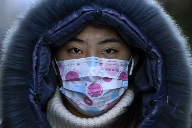 A woman wearing a face mask to help curb the spread of the coronavirus walks on a street during the morning rush hour in Beijing, Wednesday, December 16, 2020. (Photo by Andy Wong/AP Photo)