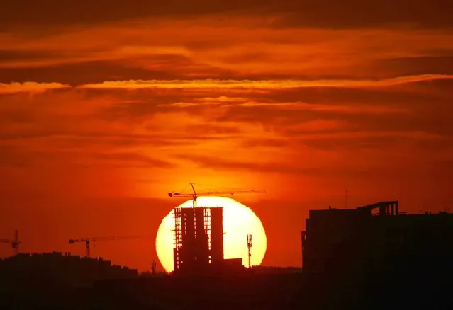 The setting sun silhouettes apartment buildings and construction cranes in Minsk, Belarus, Monday, September 14, 2015. (Photo by Sergei Grits/AP Photo)