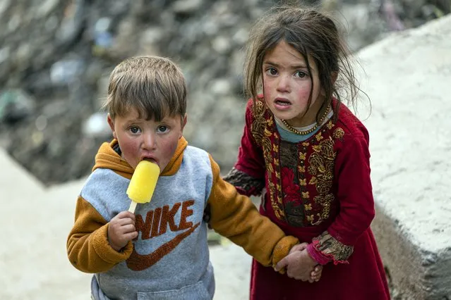 An Afghan boy eats ice cream with his sister on the outskirts of Kabul on April 6, 2023. (Photo by Wakil Kohsar/AFP Photo)
