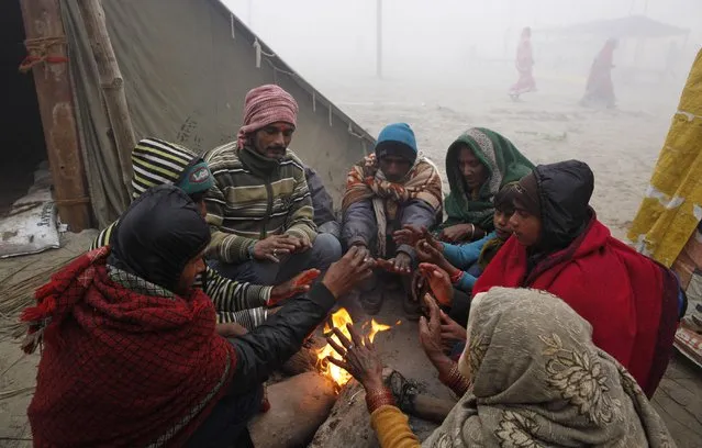 Hindu devotees warm themselves around a bonfire on a cold foggy morning after bathing in the Sangam, the confluence of rivers Ganges and Yamuna, on Makar Sankranti festival during the annual traditional fair of “Magh Mela” in Allahabad, India, Wednesday, January 14, 2015. (Photo by Rajesh Kumar Singh/AP Photo)