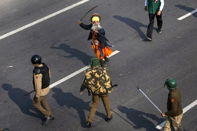 A Nihang, or a Sikh warrior, brandishes a sword at policemen as protesting farmers march to the capital breaking police barricades during India's Republic Day celebrations in New Delhi, India, Tuesday, January 26, 2021. Tens of thousands of farmers drove a convoy of tractors into the Indian capital as the nation celebrated Republic Day on Tuesday in the backdrop of agricultural protests that have grown into a rebellion and rattled the government. (Photo by Altaf Qadri/AP Photo)