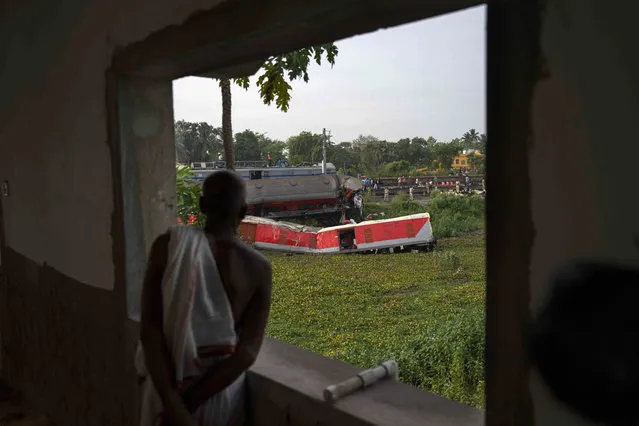 A person watches from the balcony of his house at the site where trains that derailed, in Balasore district, in the eastern Indian state of Orissa, Sunday, June 4, 2023. (Photo by Rafiq Maqbool/AP Photo)
