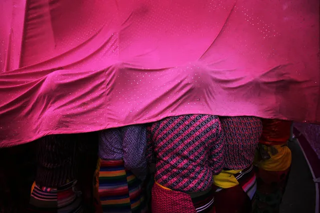 Tibetan artists living-in-exile take cover under the fabric of a canopy as they wait to perform on stage during the Himalayan Festival 2015 at McLeod Ganj near Dharamsala, India, December 10, 2015. Artists from the Himalayan region take part in the annual Himalayan Festival which is organized by the Indo-Tibetan Friendship Association (ITFA). (Photo by Raminder Pal Singh/EPA)