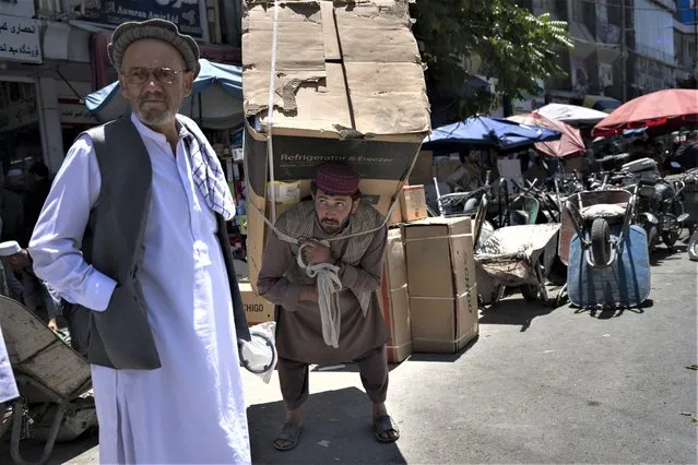 A man carries a refrigerator in a street market in Kabul, Afghanistan, Thursday, June 8, 2023. (Photo by Rodrigo Abd/AP Photo)
