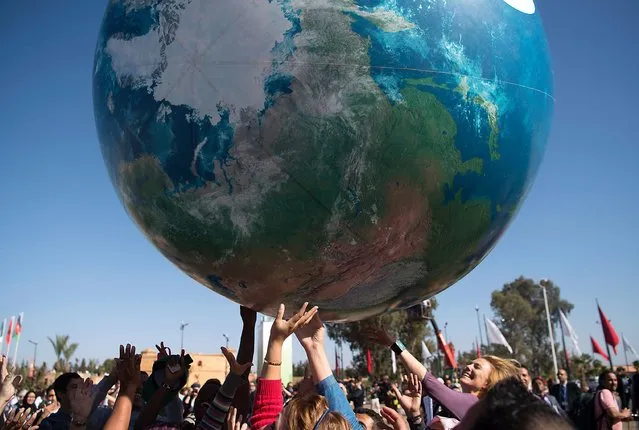 Members of International delegations play with a giant air globe ball outside the COP22 climate conference on November 18, 2016 in Marrakesh, Morocco. (Photo by Fadel Senna/AFP Photo)