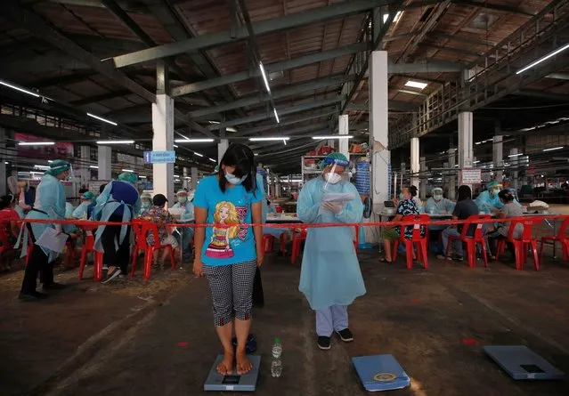 A woman has her weight measured by a medical worker prior to receiving a shot of CoronaVac vaccine against COVID-19, developed by China's Sinovac Biotech, during a mass vaccine inoculation as an effort to curb the spread of a COVID-19 pandemic cluster, at Bang Khae Market in Bangkok, Thailand, 17 March 2021. The Bangkok Metropolitan Administration starts its mass COVID-19 vaccine inoculation for 6,000 people in Bang Khae district to prevent the spread of disease after a new virus cluster was detected that spread hundreds of infections so far. (Photo by Rungroj Yongrit/EPA/EFE)