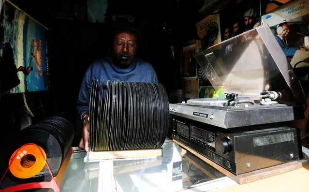 Vendor James Rugami removes vinyl records from the rays of the sun in his twin stalls that specialize in selling second-hand vinyl records and restoration of vintage players at the Kenyatta Market in Nairobi, Kenya November 24, 2016. (Photo by Thomas Mukoya/Reuters)