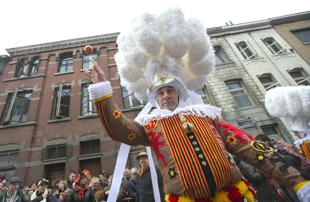 A Gille of Binche throws an orange while taking part in the parade during the carnival event in Binche February 17, 2015. (Photo by Yves Herman/Reuters)