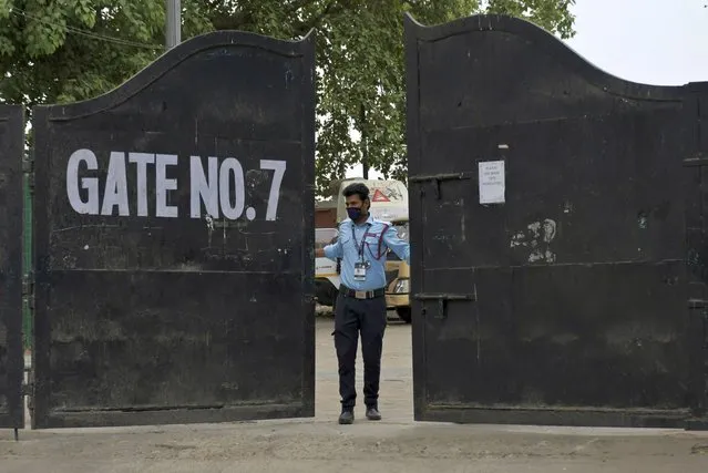 A security guard closes the gate of Arun Jaitley Stadium, one of the six venues of Indian Premier League 2021, in New Delhi, India, Tuesday, May 4, 2021. The Indian Premier League was suspended indefinitely on Tuesday after players or staff at three clubs tested positive for COVID-19 as nationwide infections surged. (Photo by Ishant Chauhan/AP Photo)