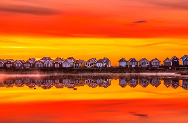 The sun rises above Mudeford beach huts in Dorset, United Kingdom with a colourful sky on March 15, 2023. There are about 360 wooden beach huts at Hengistbury Head, Mudeford Spit Sandbank. The huts regularly sell for over £300,000 in addition to £4,500-a-year in rates. (Photo by Steve Hogan/Picture Exclusive)