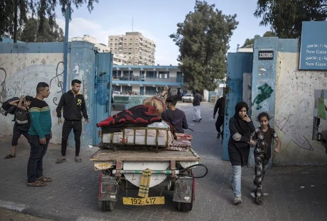 Palestinians flee their homes to a U.N. school after overnight Israeli heavy missile strikes on their neighborhoods in the outskirts of Gaza City, Friday, May 14, 2021. (Photo by Khalil Hamra/AP Photo)