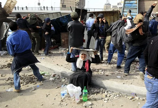 A woman opposition supporter takes shelter while providing water during rioting with pro-Mubarak demonstrators near Tahrir Square in Cairo February 3, 2011. (Photo by Goran Tomasevic/Reuters)