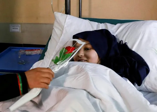A schoolgirl who was injured in the blast receives flowers from a student at a hospital in Kabul, Afghanistan on May 10, 2021. (Photo by Reuters/Stringer)